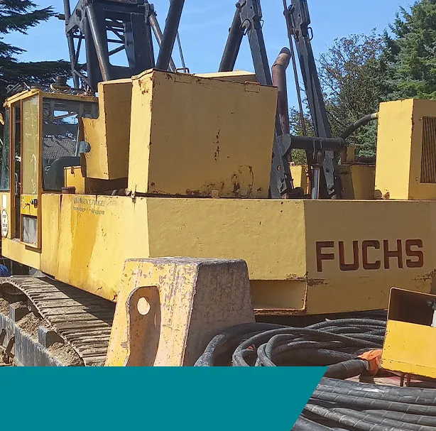 Engin de manutention Fuchs jaune avec bras hydraulique et flexibles mécaniques en extérieur.