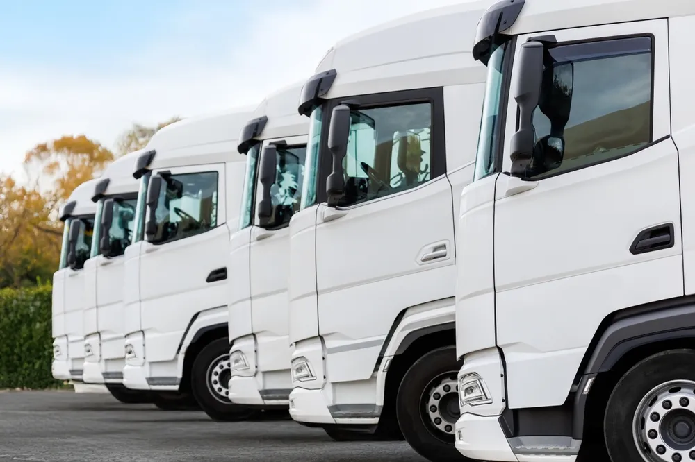 Rangée de camions poids lourds blancs stationnés en extérieur.